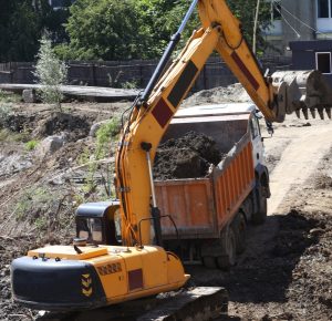 a modern crawler excavator excavates soil and loads it onto a truck during construction work